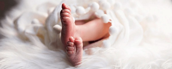 Baby feet wraped in white feather sheet